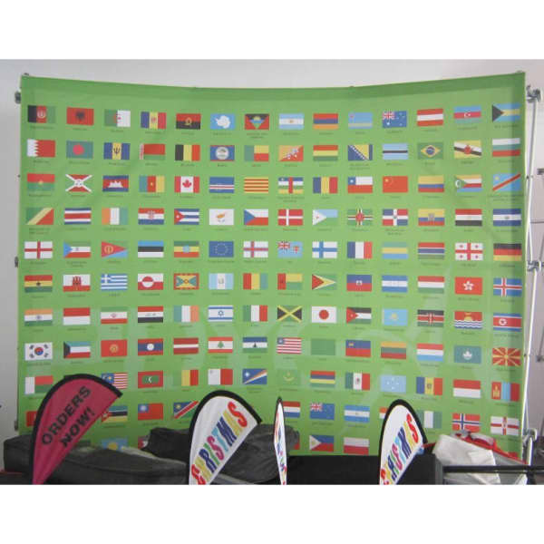 A fabric media wall featuring various flags on a green background, displayed alongside two promotional banners.