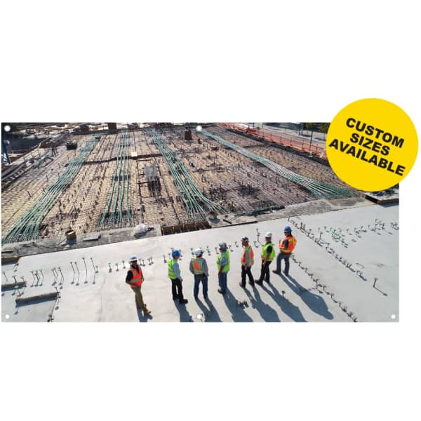 A group of construction workers in safety gear on a building site, overlooking a partially constructed structure.