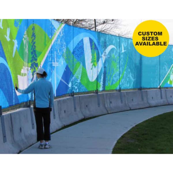 A woman in a blue top interacts with a vibrant, multicoloured Polyester Fence Mesh, featuring abstract designs.