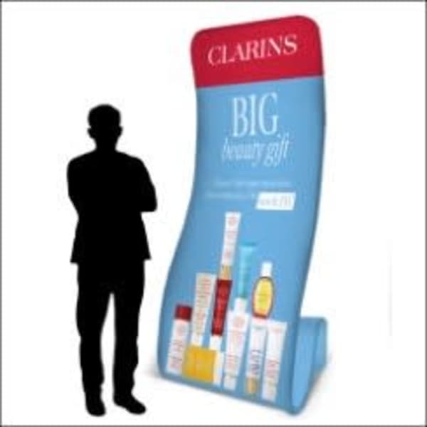 A promotional display in blue featuring various beauty products, with a silhouette of a person next to it.