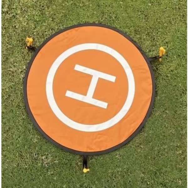 An orange drone landing mat with a white 