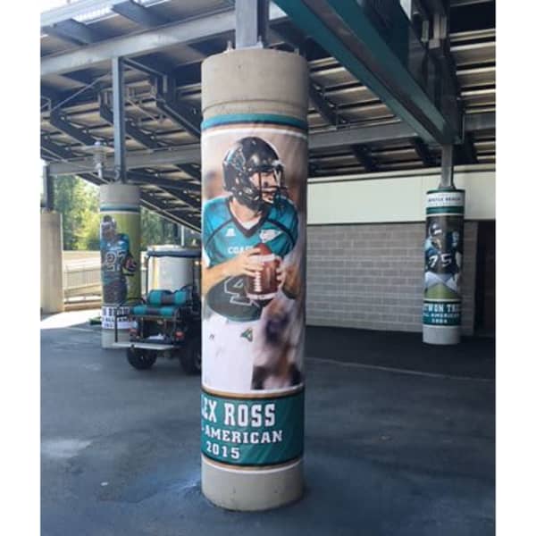 Promotional vinyl banner wraps featuring a football player in a teal uniform on concrete pillars.