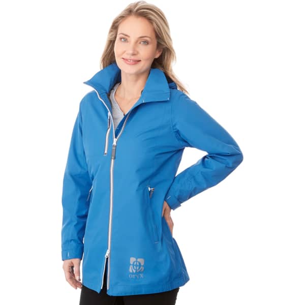A woman wearing a bright blue rain jacket with a zip and a logo on the front.