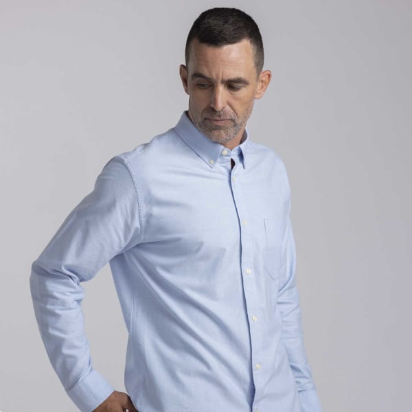A men's button-up shirt in light blue with a collar and a chest pocket, featuring a simple design.