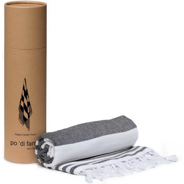 A grey and white striped Patara Turkish towel rolled neatly beside its cylindrical packaging featuring a logo.