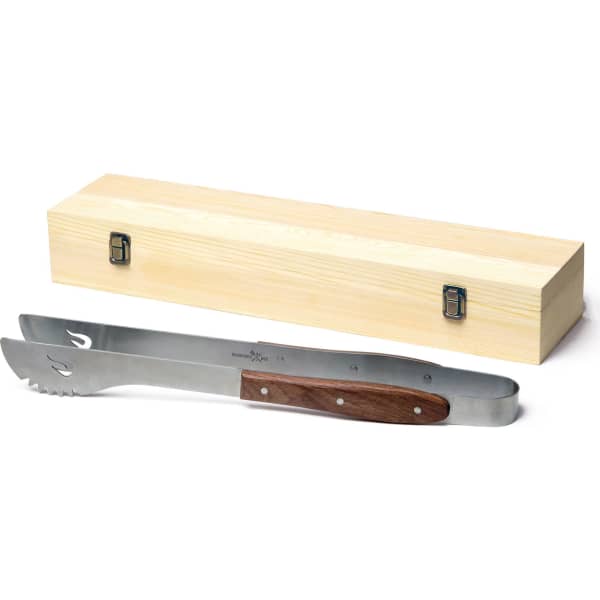 A pair of stainless steel BBQ tongs with a wooden handle, placed next to a wooden storage box.