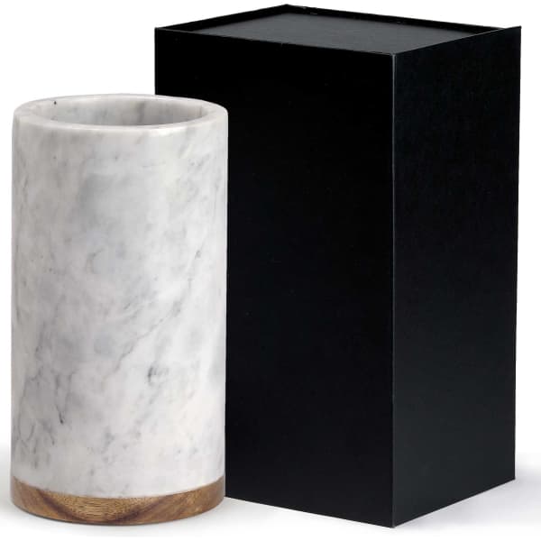 A marble drink cooler in white with a wooden base, alongside a black gift box.