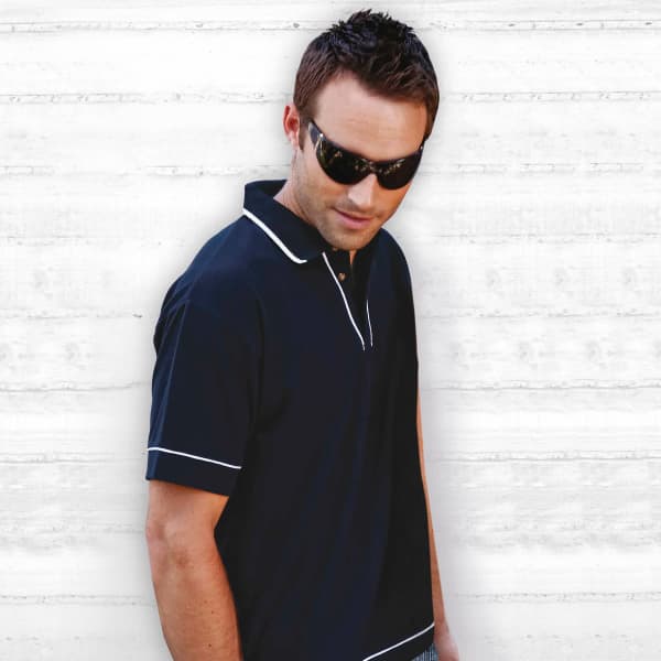 A black polo shirt with white trim, featuring a logo, displayed by a model wearing sunglasses against a light background.