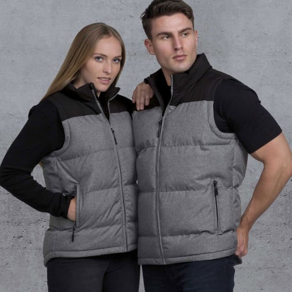 A grey and black puffa vest worn by two models, featuring zippered pockets and a logo.