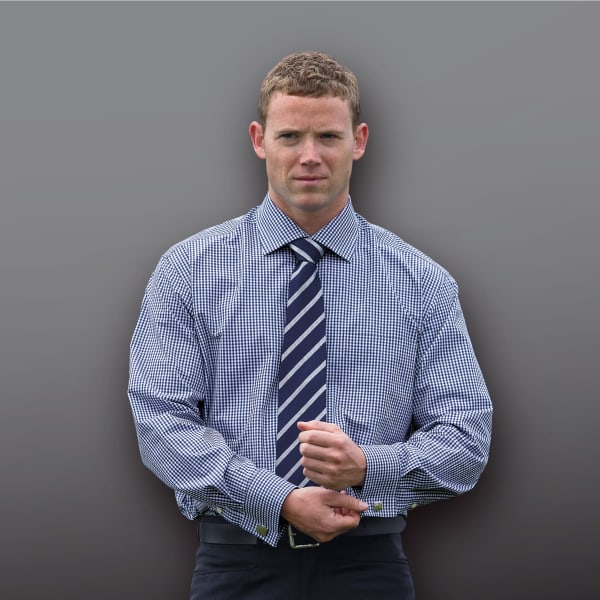 A check patterned button-up shirt in blue and white, worn with a navy and white striped tie. The model is adjusting his shirt cuffs.