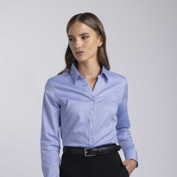 A women's button-up shirt in light blue with a collar and long sleeves, featuring a subtle logo.