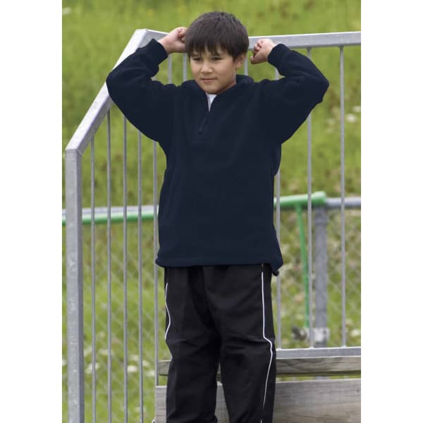 A black polar fleece pullover worn by a young boy, standing on a metal structure in an outdoor setting.