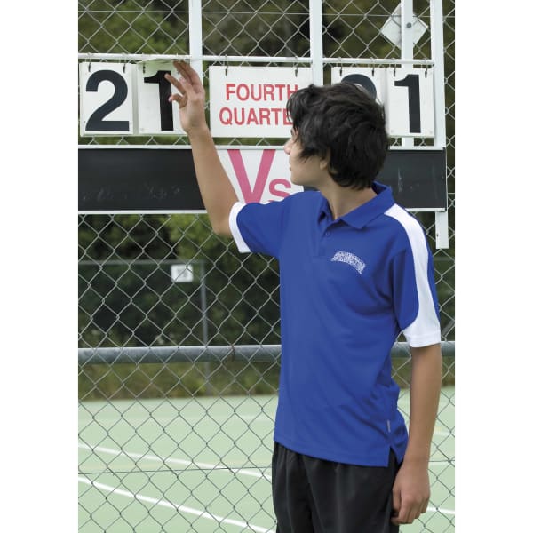 A young person wearing a blue and white polo shirt adjusts a scoreboard on a tennis court. The shirt has a logo.