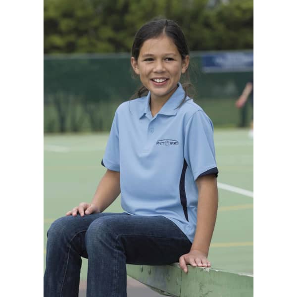 A girl wearing a light blue polo shirt with a logo, sitting on a bench at a sports facility.