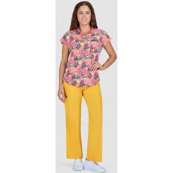 A floral print top with a bright pink background and yellow pants, paired with white shoes. The model is smiling.
