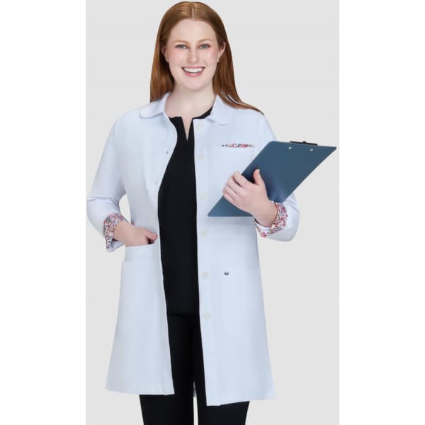 A lab coat in light blue with patterned cuffs, held by a smiling woman, with a clipboard in her hands.