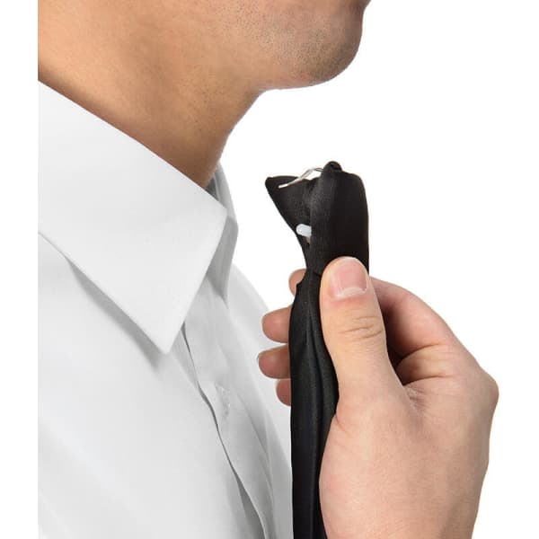 A person holding a black Clip Tie near their neck, wearing a white shirt. The product features a logo.