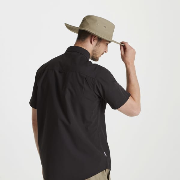 A man wearing a beige Kiwi ranger hat and a black short-sleeve shirt, viewed from behind. The hat features a logo.