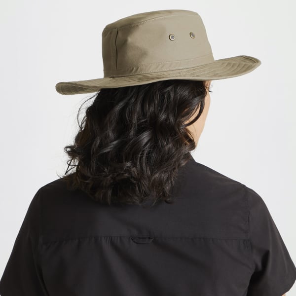 A beige Kiwi ranger hat with eyelets, worn by a person with wavy dark hair, seen from behind.
