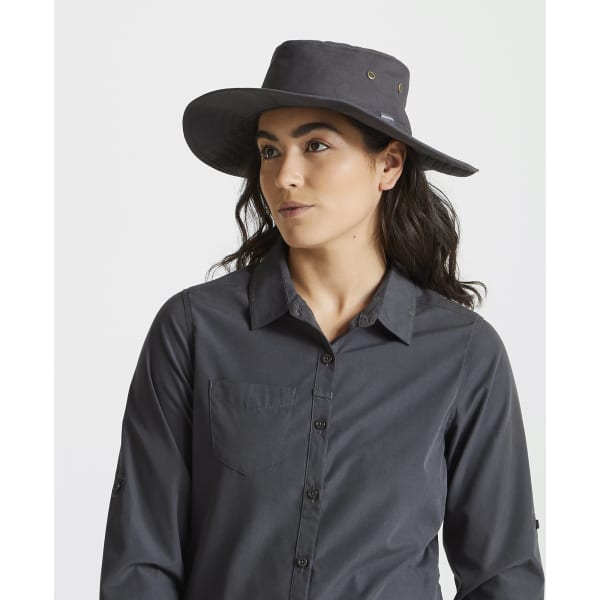 A grey Kiwi ranger hat styled with a wide brim, worn by a person in a button-up shirt. The hat features a logo.