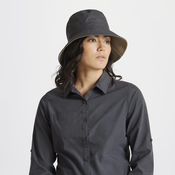 A woman wearing a reversible grey sun hat, paired with a matching button-up shirt. The hat features a logo.