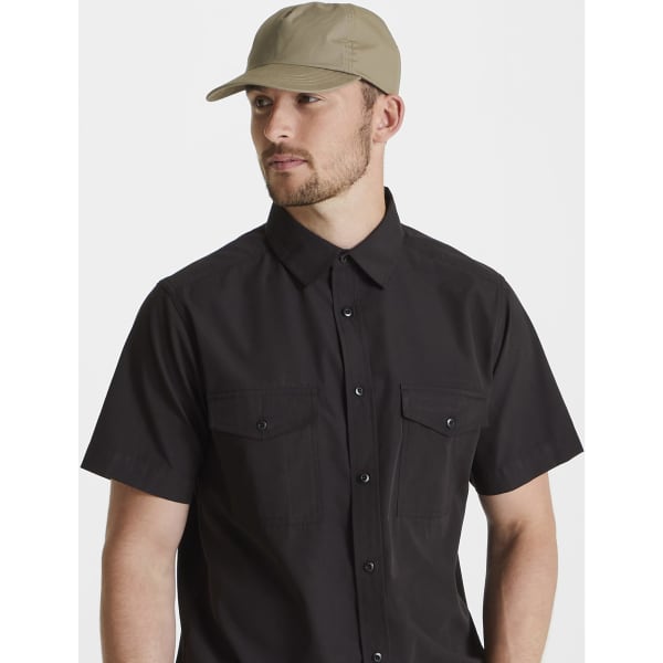 A man wearing a light brown "Kiwi cap" paired with a black button-up shirt, viewed from the side.