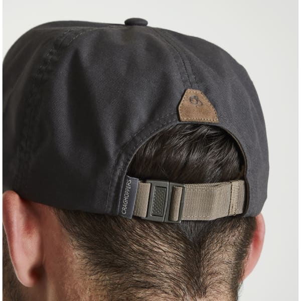 A black trucker cap with a brown leather patch and adjustable strap, seen from the back.