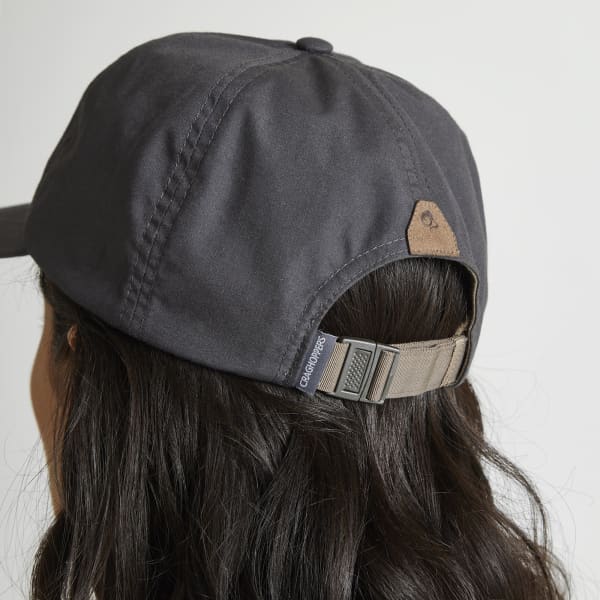 A dark grey trucker cap with a logo and an adjustable strap at the back, worn by a person with long hair.