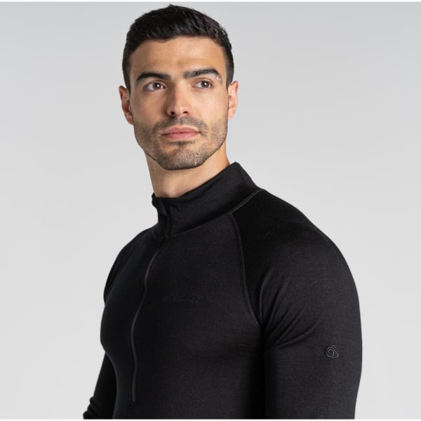 A black Merino half zip long sleeve baselayer top on a male model, featuring a logo on the sleeve.