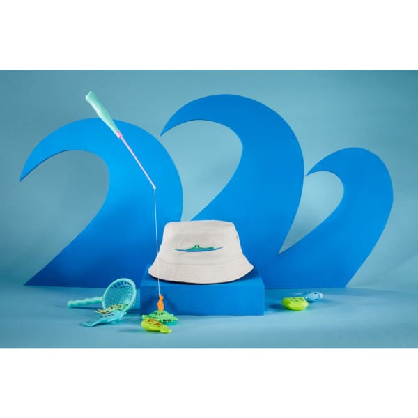 A white fisherman piping hat displayed against blue wave backdrops, surrounded by fishing toys in turquoise and green.