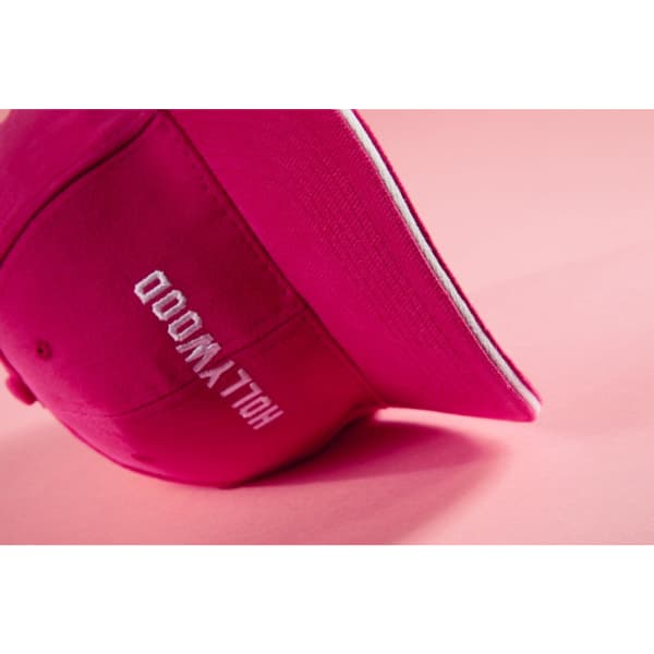 A pink 6 panel sandwich cap with a curved brim, featuring a logo on the side.