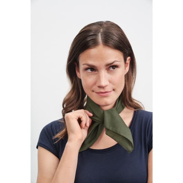 A bandana in olive green, tied around the neck of a model with long brown hair, featuring a branded logo.