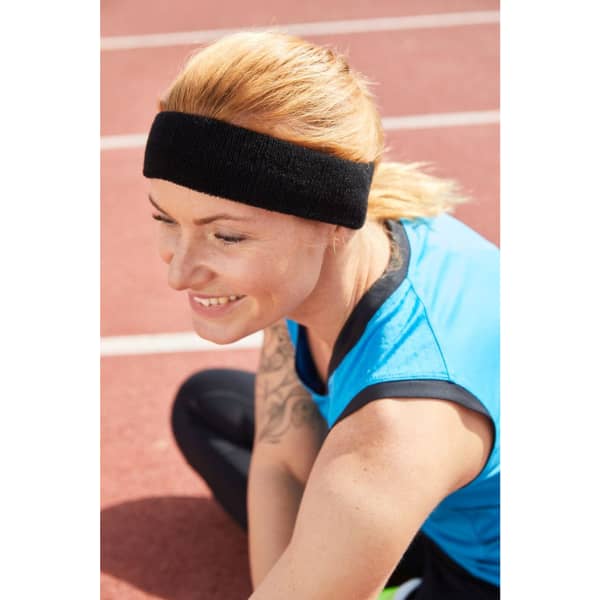 A black Terry headband worn by a woman with blonde hair, seated on a track. She is wearing a blue athletic top.
