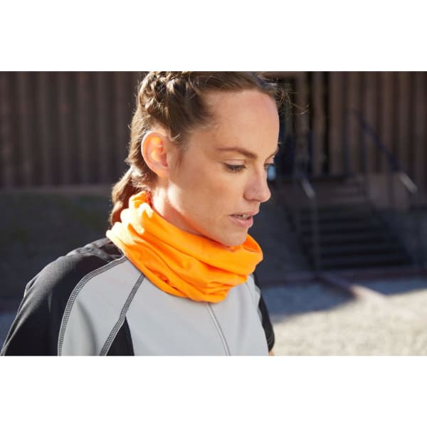 A headband in bright orange, worn as a neck gaiter by a woman in a grey athletic top. Features a logo.