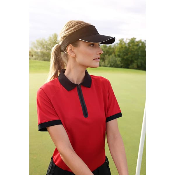 A sporty red polo shirt paired with a black Sandwich Sunvisor, worn by a woman on a golf course.