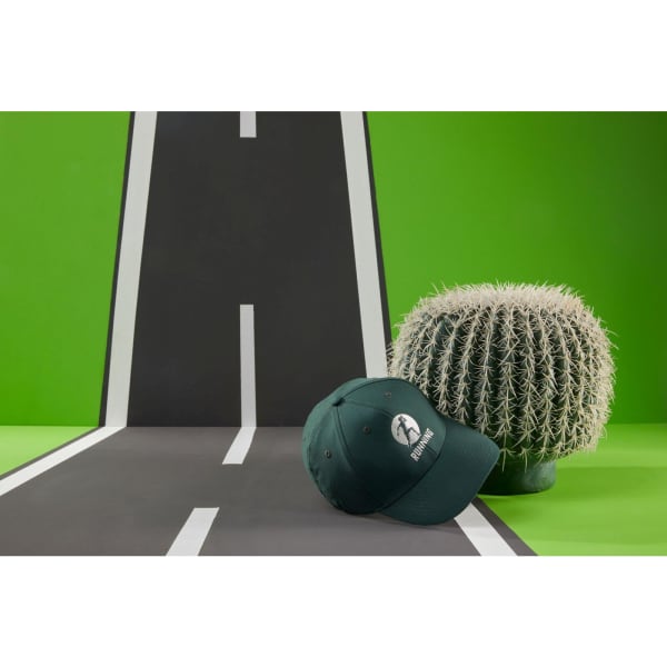 A dark green 6 panel polyester cap with a logo, placed near a cactus on a stylised road backdrop.