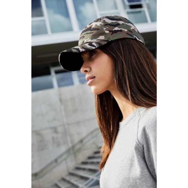 A camouflage 6-panel cap featuring a curved brim, worn by a model with long hair. It has a logo on the front.