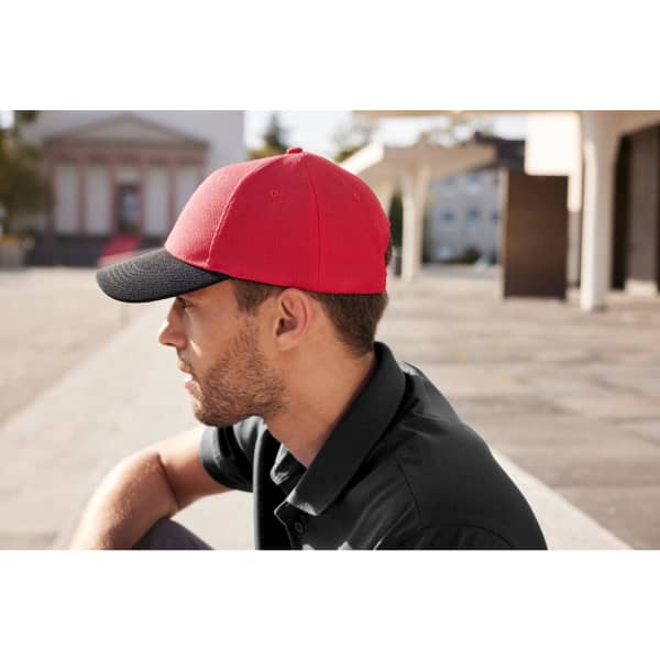 A red and black six-panel mesh cap worn by a man, set against an outdoor background.