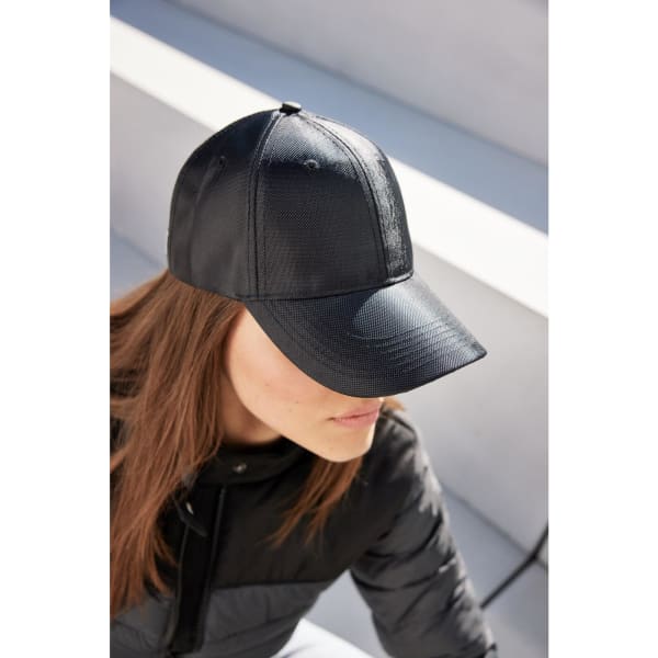 A black 6 panel cap with a curved brim, featuring a logo on the front, worn by a woman with long hair.
