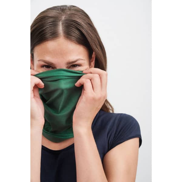 A young woman holds a green polyester bandanna near her face, wearing a dark top. The product has a logo.