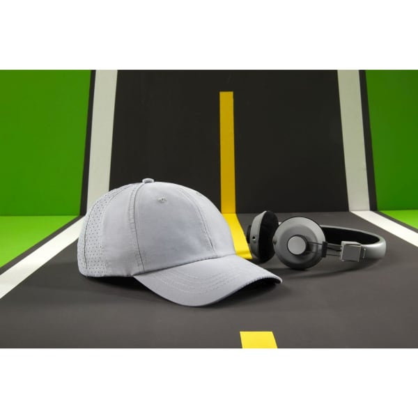 A light grey cap with a mesh panel, positioned beside a pair of black and silver headphones, set against a vibrant background.