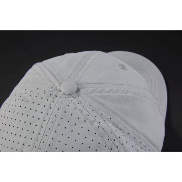 A light grey cap with laser cut holes for ventilation and a metal button on top, featuring a logo.