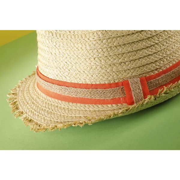 A straw hat with a frayed edge and a coral band, set against a green background.