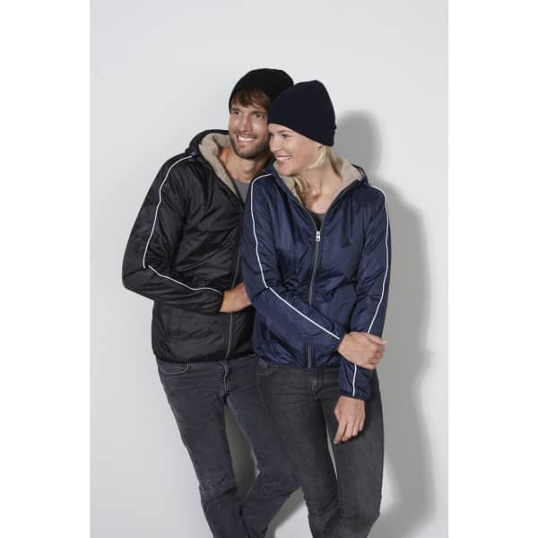 A man and woman wear matching jackets in black and navy, each sporting a knitted beanie, in a casual pose.