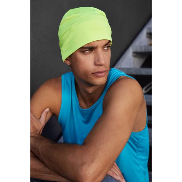 A bright yellow running beanie worn by a person in a blue tank top, sitting with arms crossed.
