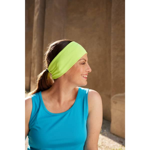 A running headband in bright yellow-green worn by a woman with long hair, paired with a blue tank top.
