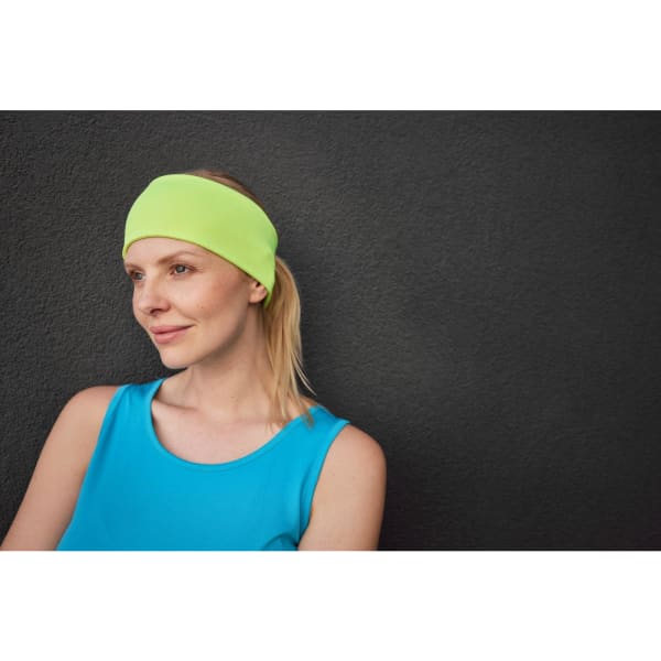 A running headband in bright lime green worn by a woman with blonde hair, against a dark background.