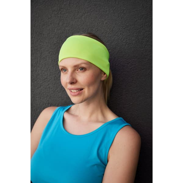 A running headband in bright yellow, worn by a woman in a blue tank top, set against a dark background.