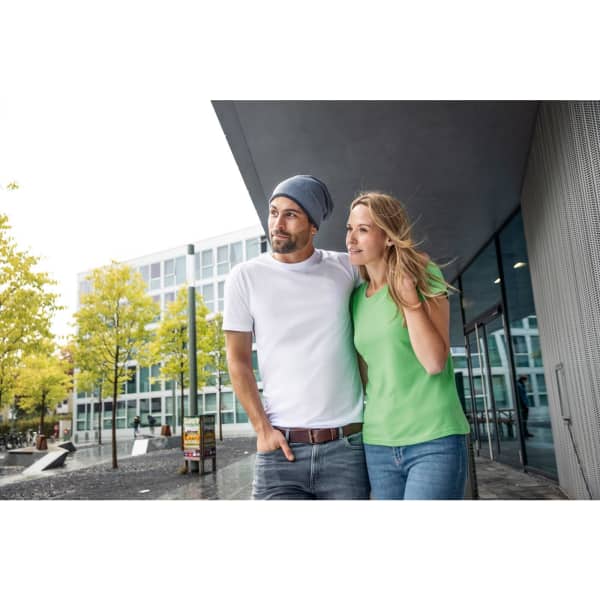 A fleece beanie in grey worn by a man, alongside a woman in a green t-shirt, in an outdoor urban setting.