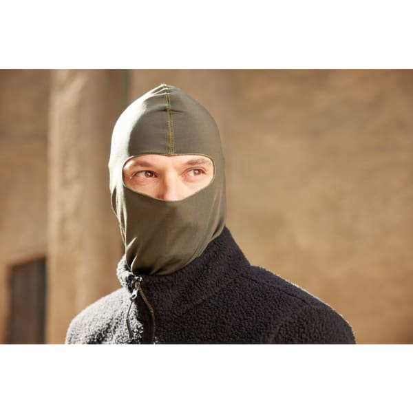 A balaclava in olive green, worn by a person, with a zippered black jacket in the background.